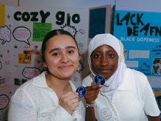 Students show their medals from Project Invent while standing in front of their project poster.